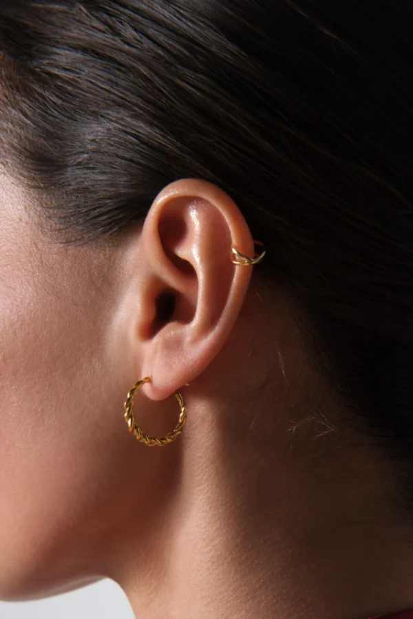 kolczyk skrecony koło pozlacany kolczyk koło skręcony z nausznicą skrzyzowane koła w zbliżeniu na uchu modelki