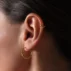 kolczyk koło skręcony z nausznicą skrzyzowane koła w zbliżeniu na uchu modelki