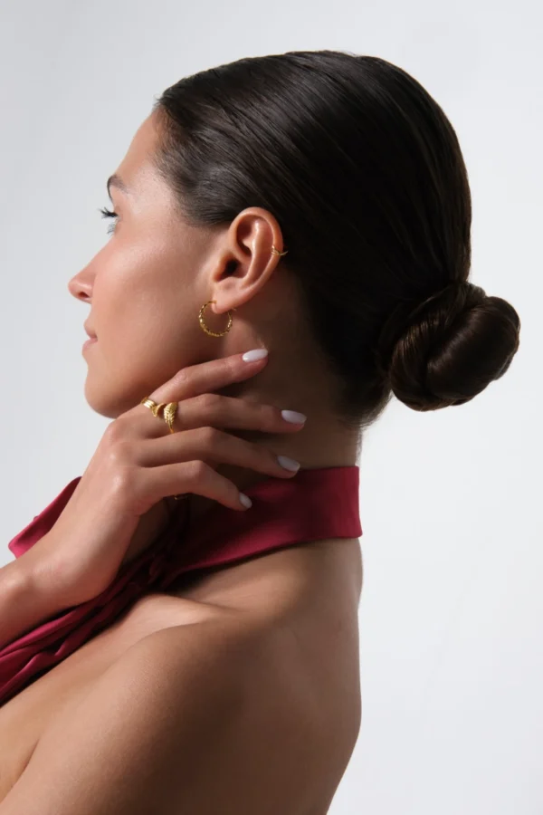 kolczyk skrecony piersionek i nausznica modelka bokiem prezentujaca kolczyki skręcone koła, nausznicę i pierścionki