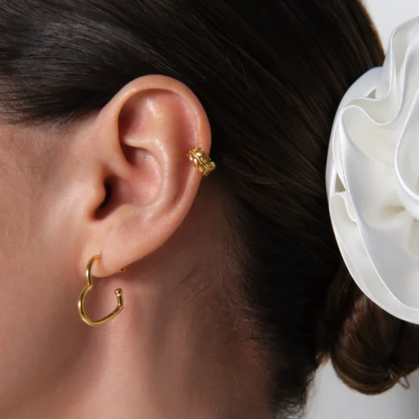 kolczyki serca azurowe i nausznica listki zbliżenie na kolczyki ażurowe serca na sztyft i nausznice listki na uchu modelki