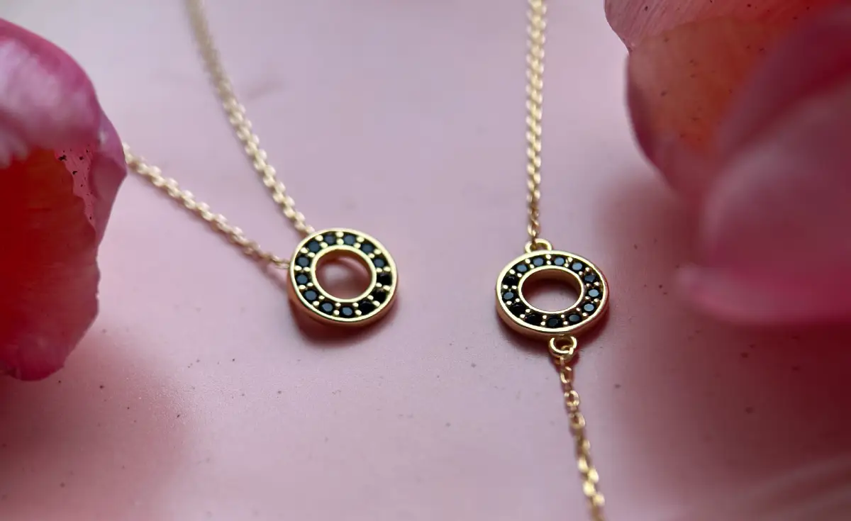 bransoletka i naszyjnik z czarnymi cyrkoniami obok kwiatów