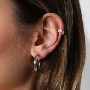 zbliżenie na ucho z nausznicą w kształcie gałązki i kolczykami skręconymi kołami