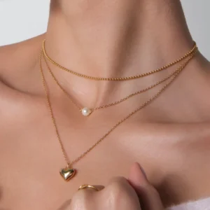 stylizacja naszyjników, z kuleczkami, z perłą, i serduszkiem na szyji modelki