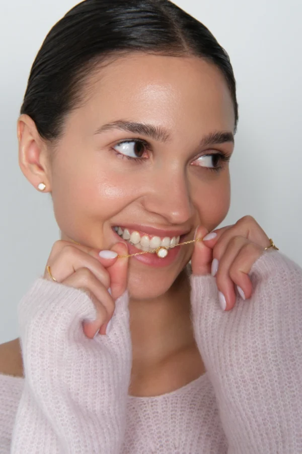 zestaw opal 1 modelka prezentuje w zębach naszyjnik z opalem pozłacany i kolczyki z opalem