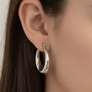 Masywne srebrne kolczyki koła 2,5 cm szerokość 0,5 cm marka Lukier Jewellery na uchu modelki, piękne i eleganckie